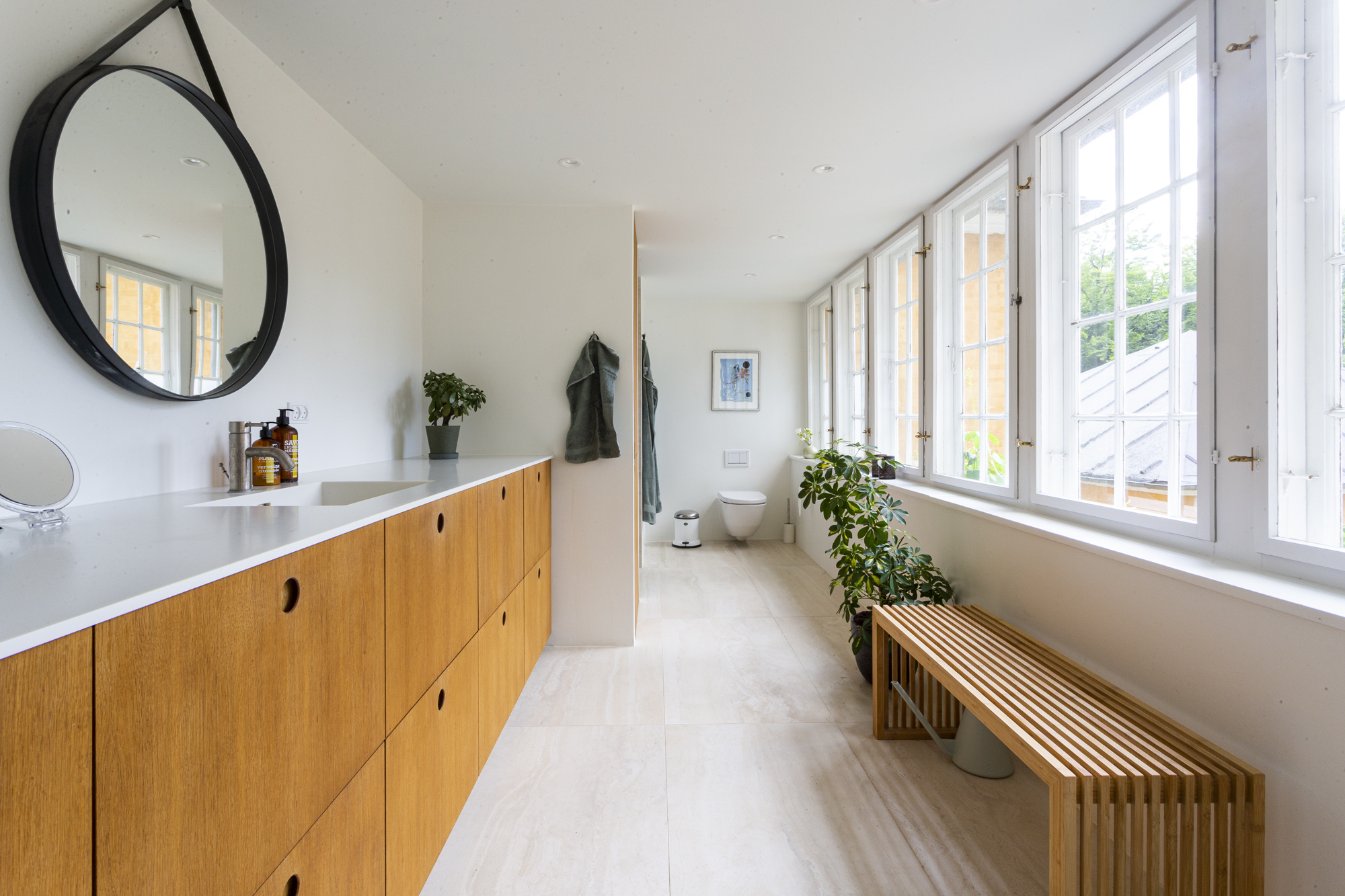 Badeværelse med stor trækommode, spejl og hvidt toilet